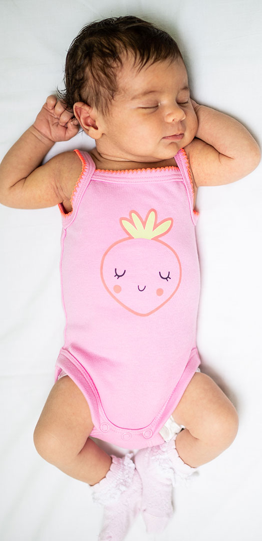Sleeping baby in pink outfit with strawberry design.