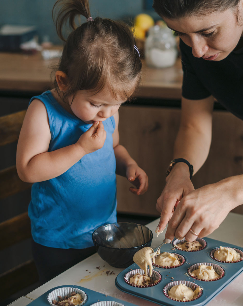 Mother and toddler spooning batter into muffin tin