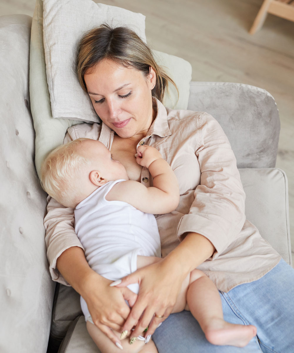 Mother breastfeeding baby while sitting on couch