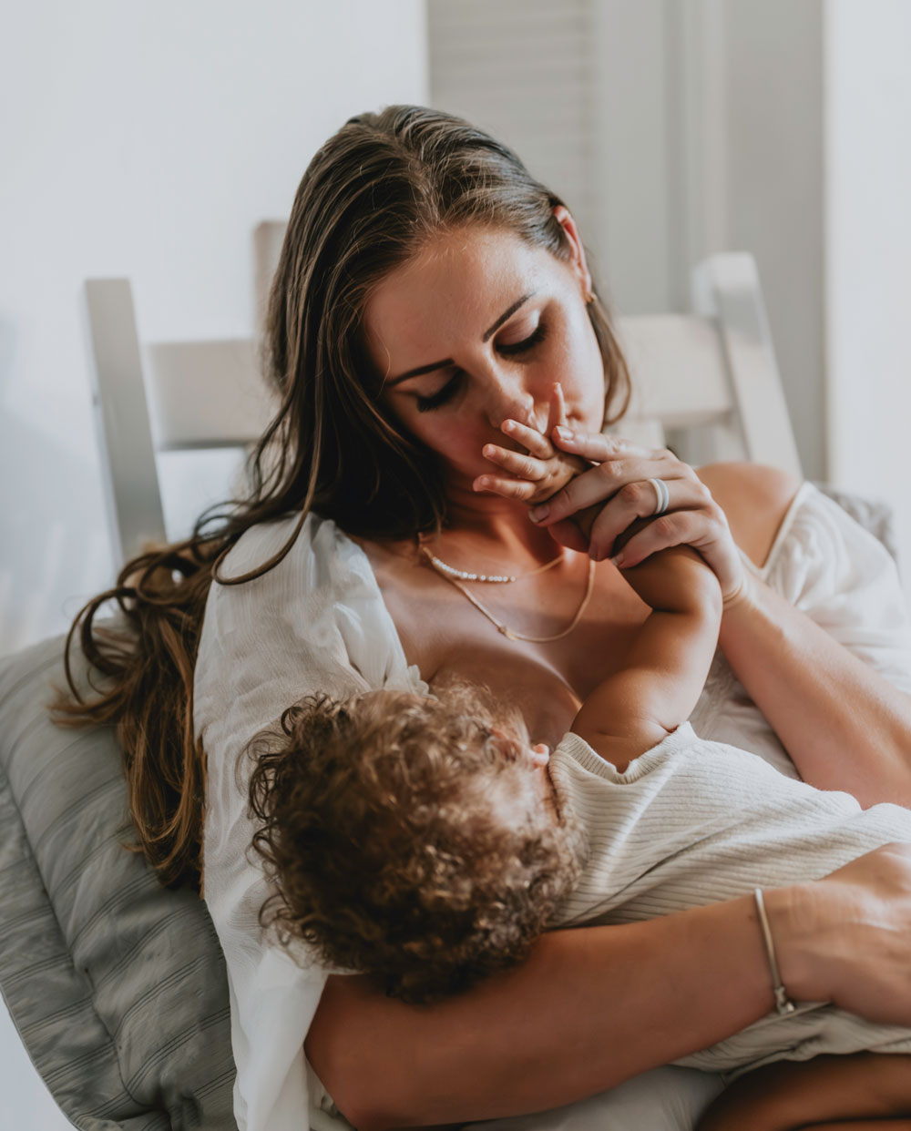 Mother kissing babys hand while breastfeeding