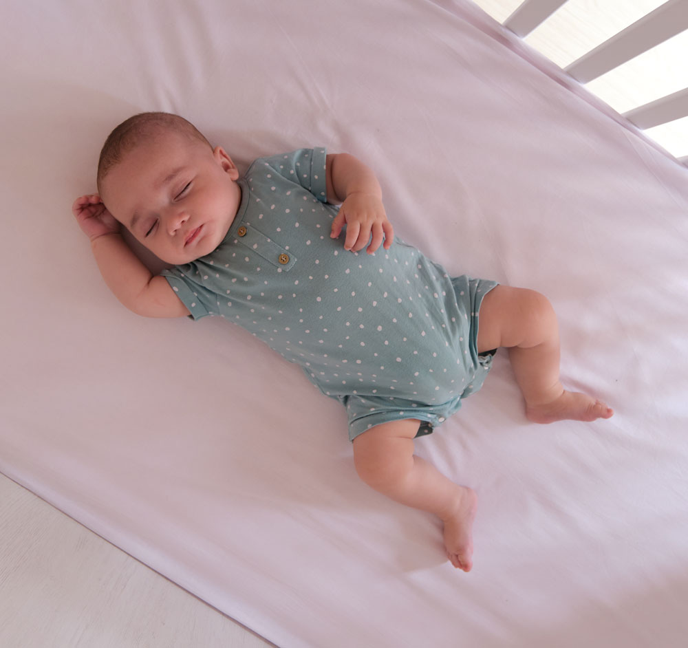 Baby sleeping peacefully on its back in crib