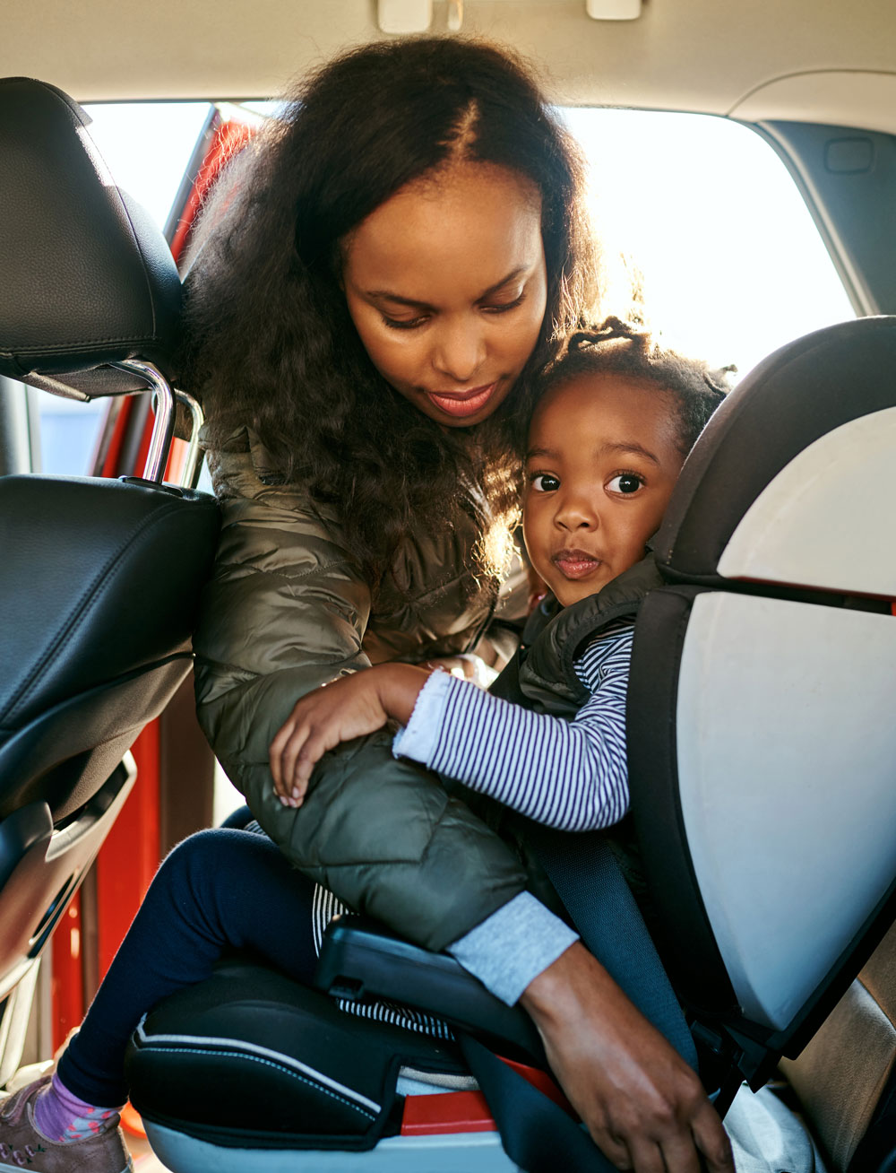 Mother buckling child into car seat safely