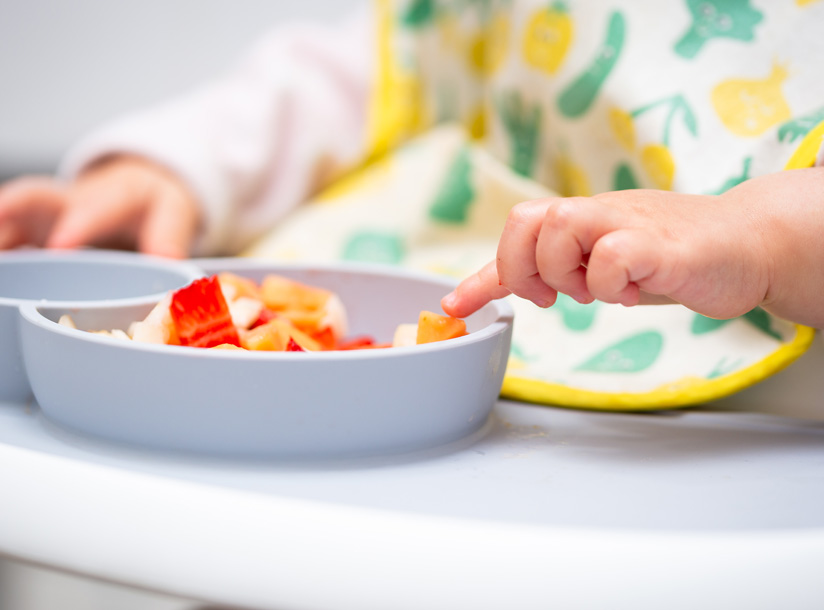 Baby self-feeding in highchair