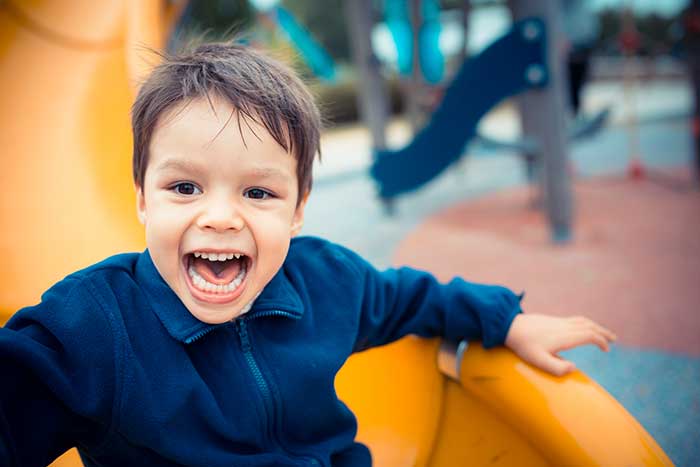 Child laughing joyfully on a playground slide.