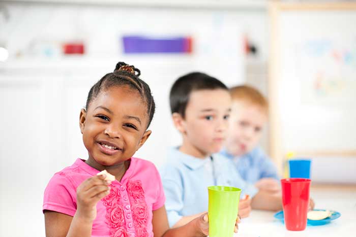 Children enjoying snacks at a colorful table.